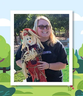 Woman smiling and holding a small scarecrow