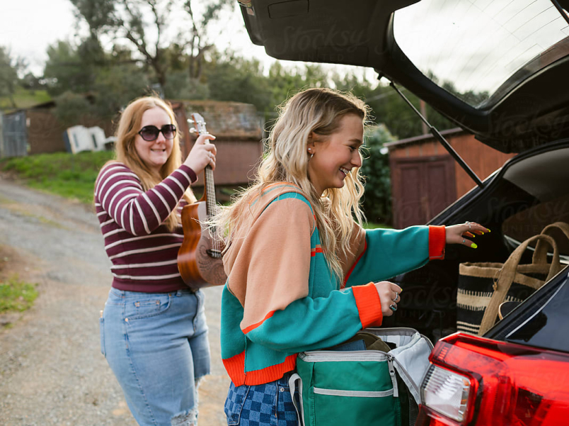 Two girls offloading car trunk